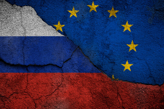 Full frame photo of a weathered flags of Russia and European Union (EU) painted on a cracked wall.