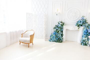 Beautiful luxury classic white bright clean interior bedroom in baroque style with large window, armchair and flower composition.