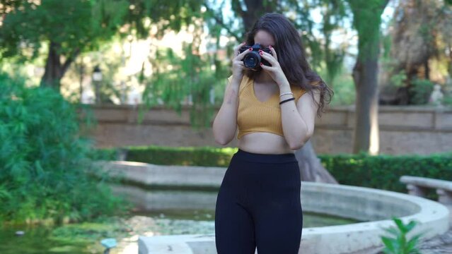 Young woman taking pictures with a vintage DSLR film camera in the park