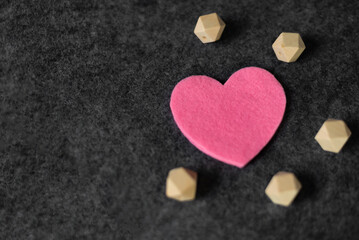 Pink felt heart on a dark gray background. scattered wooden cubes. St. Valentine's Day, Valentine's Day. top view