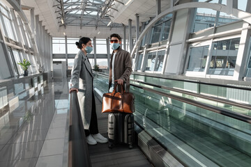 Couple in masks on moving walkway