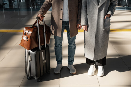 Crop couple with luggage in airport terminal