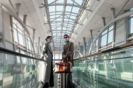 Travelers in masks on moving walkway