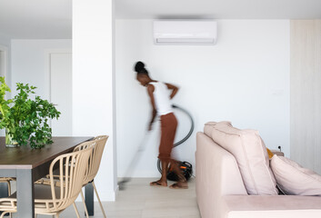 African housekeeper cleaning living room