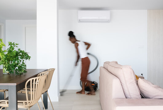 African housekeeper cleaning living room
