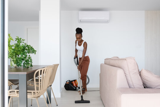 Black female tidying modern living room