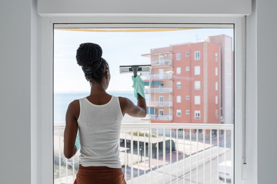African female washing window in daytime