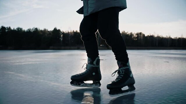  Man practicing ice skating on a clear frozen lake on a sunny winter day. Ice skating lifestyle in nature. Man skating on a frozen lake making ice sparkle. High quality 4k footage