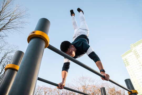 Sportsman doing handstand on bars