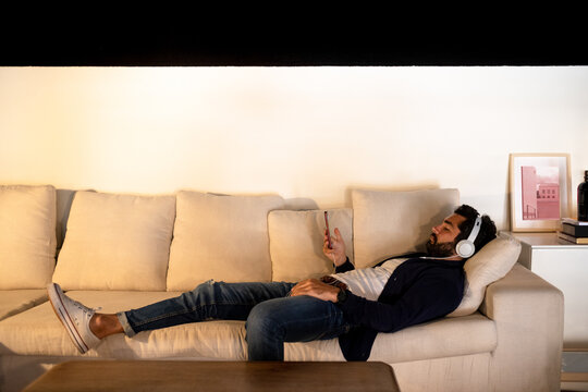 Man laying down on the sofa listening music
