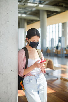 Woman wearing facial mask at the airport with backpack