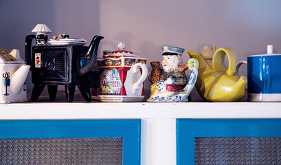 Many different tea pots on cupboard 