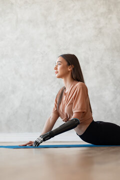 Woman with a prosthesis on her arm doing yoga at home