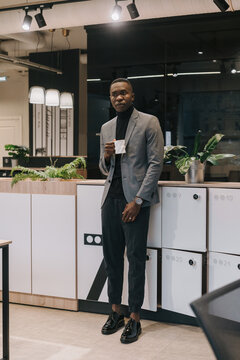 A black man in a business suit with a cup in his hand