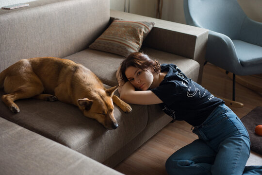 tired girl near a sleeping dog on the couch
