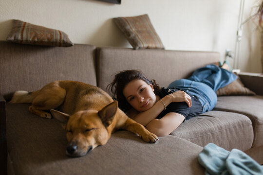a girl and a red dog lie on the couch next to
