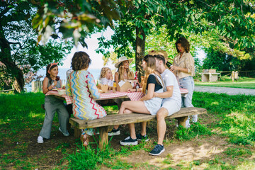 Cheerful friends having picnic in garden