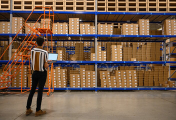 Hipanic manager with laptop computer doing inventory 