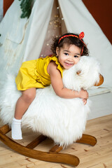 little african, black girl is rocking on a rocking-horse. baby with dark skin color smiling