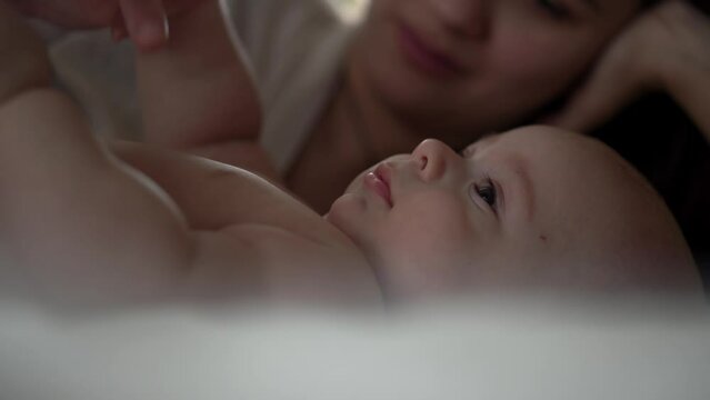 Newborn Baby With Young Mom look Into Each Other Eye. Cute Smiling Teethless Kid Face Portrait. Woman Kissing With Child Look At Camera. Infant, Mother Day, Childbirth, Beginning, Relationship Concept