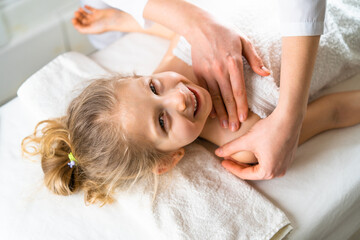 a woman gives a massage to a little girl, children's massage, prevention of scoliosis, osteopathy