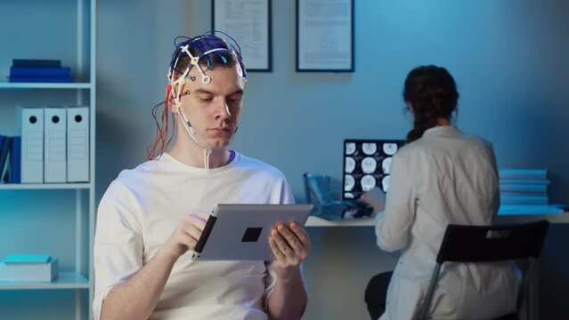 EEG topographer for examining brain, doctor making electrogram of scalp activity. Researching of brain work, man using gadget wearing electroencephalography headset.