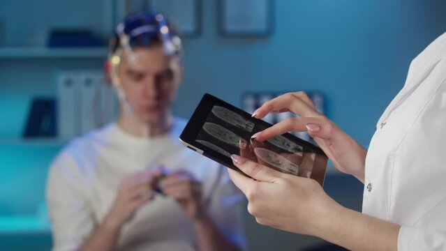 EEG topographer for examining brain, doctor making electrogram of scalp activity. Researching of brain work man wearing electroencephalography headset and holding cube.