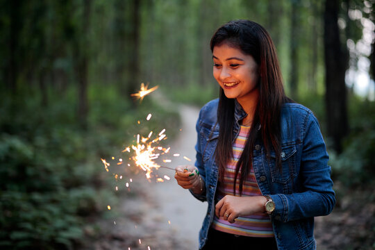 Beautiful Indian girl smiling with sparkler at forest