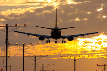 Commercial airplane landing in sunset at a runway