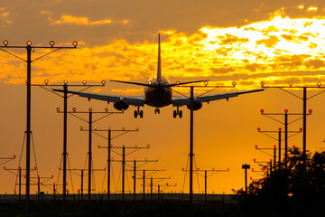 Commercial airplane landing in sunset at a runway