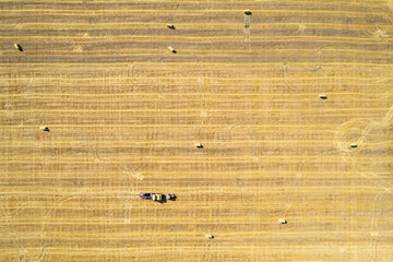 Drone view on field with tractors making straw bales