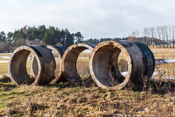 Old used concrete tubes in the field. Well liner.