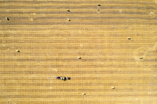 Drone view on field with tractors making straw bales