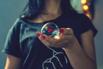 Mujer sosteniendo una bola de cristal con reflejo de corazón