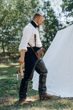 A bearded man in vintage clothing with an ax