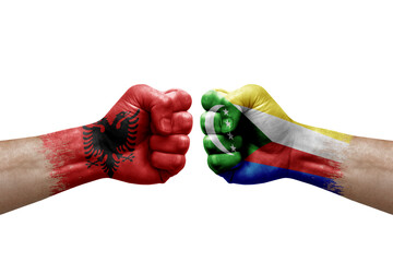 Two hands punch to each others on white background. Country flags painted fists, conflict crisis concept between albania and comoros