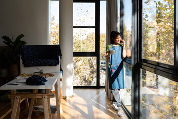 Woman calling by phone near the window in apartment