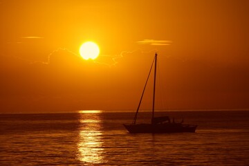 Sailboats and a beautiful red and orange sunset Silhouettes of yachts  in the tropical sea ocean boat catamaran sailing zanzibar - obrazy, fototapety, plakaty