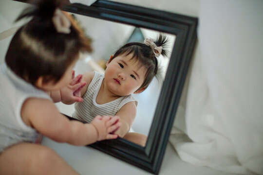 Asian baby touching mirror