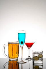 Cocktails and beer, beer mug, virgin mojito, Cosmopolitan and curacao drink on glass table and white background with space for text