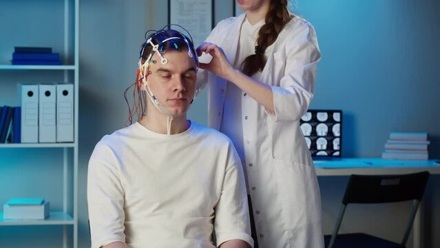 EEG topographer for examining brain, doctor making electrogram of scalp activity. Researching of brain work man wearing electroencephalography headset. 