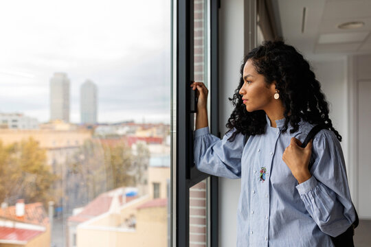 Stylish woman looking out the apartment window