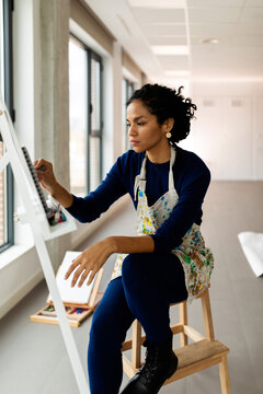 Skillful woman painting on easel at studio