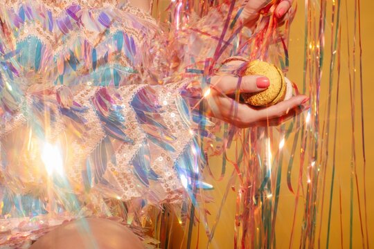 Anonymous woman in sparkling dress holding macaroons