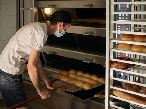 Baker at work at the oven with shovel and baking goods