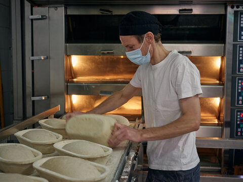 Baker at work preparing bread loafs for oven