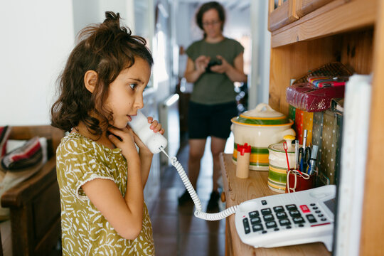 7-year old kid speaking on home line telephone 