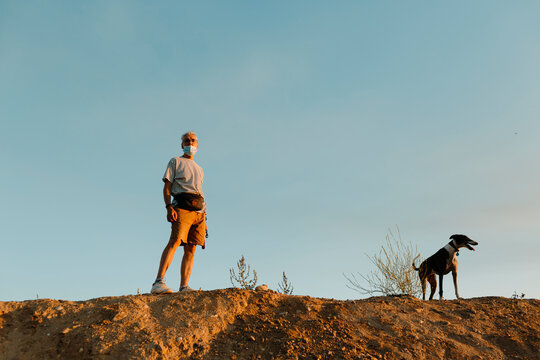 man with face mask and dog at sunset