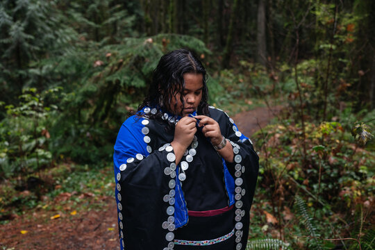 Woman fastening buttons on regalia dress.