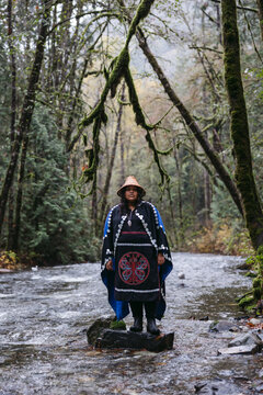 Woman standing in river wearing indigenous regalia